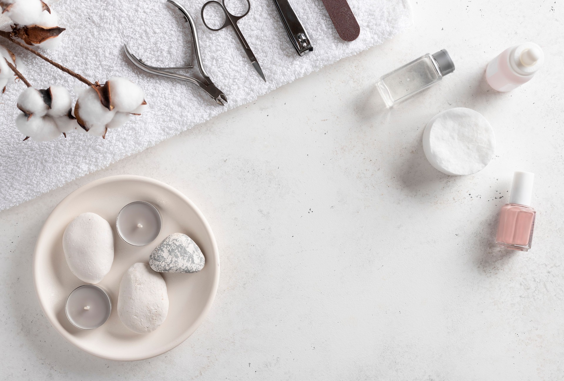 manicure tools on a white bath towel, nail polish remover, cuticle oil and nude nail polish. frame border for a beauty salon.